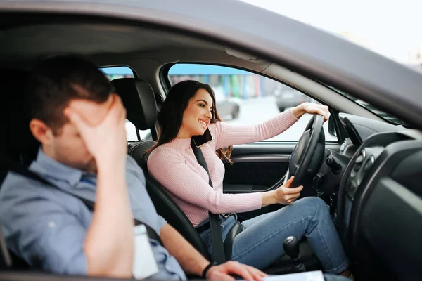 Homme instructeur auto prend examen chez la jeune femme. Shamedguy assis à côté étudiant négligent qui conduit la voiture et parler au téléphone en même temps . — Photo
