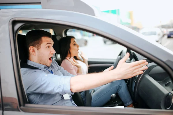 Maschio istruttore di auto prende esame in giovane donna. L'uomo spaventato e spaventato punta in avanti con entrambe le mani. Femmina stident driwing senza volante. modello spaventato urlando . — Foto Stock