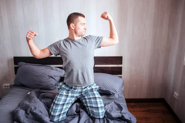 Um homem de barriga de panela fica na cama e grimeiras. Frick, divertido conceito masculino modelo casa — Fotografia de Stock