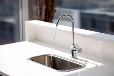 arıtılmış su filtrenin çelik musluğundan akıyor.