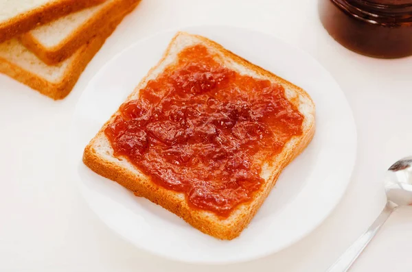 Toast mit zerknüllter Apfelmarmelade auf einem Teller auf weißem Tisch. leckeres süßes Frühstück. — Stockfoto