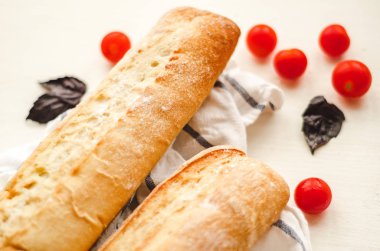 Taze baget ile bir net üzerinde beyaz bir havlu kiraz domates ve fesleğen ile masaya. Vejetaryen kahvaltı.