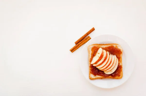 Tostada con mermelada de manzana y rodajas de manzanas frescas en plato sobre una mesa blanca. Delicioso desayuno dulce. Vista superior . — Foto de Stock