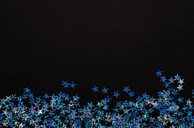 Folyo siyah arka plan üzerine parlak mavi yıldız. Festival konfeti.