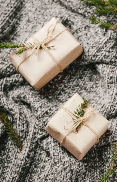 Gift boxes on a warm knitted gray plaid with Christmas tree branches. A cozy new year. — Stock Photo, Image