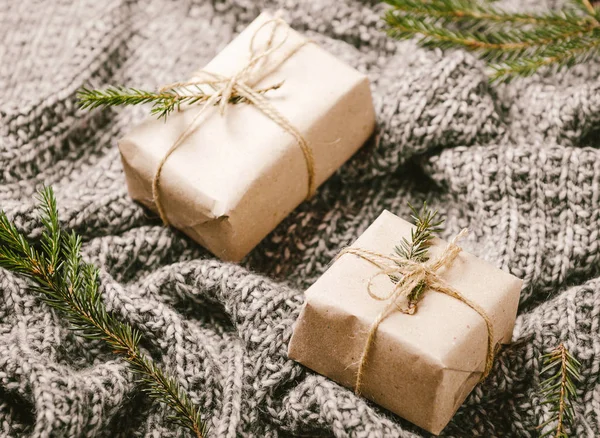 Coffrets cadeaux sur un plaid gris tricoté chaud avec des branches d'arbre de Noël. Une nouvelle année confortable . — Photo
