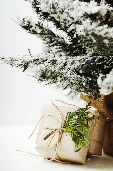 Cajas bajo un árbol artificial y nieve. Regalos de Santa Claus. Estilo rústico — Foto de Stock