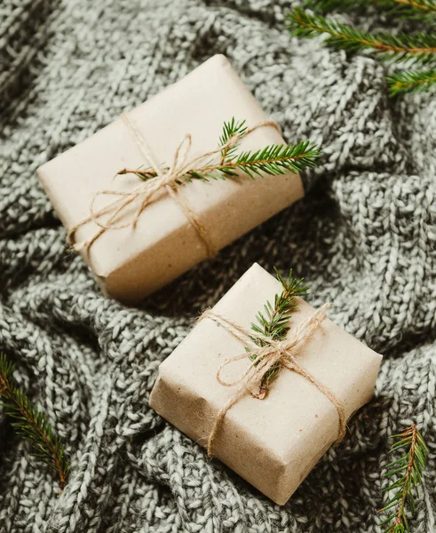 Scatole regalo su un caldo plaid grigio lavorato a maglia con rami di albero di Natale. Un nuovo anno accogliente . — Foto Stock