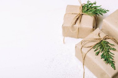 Beyaz arka plan ve sanatsal kar kraft kağıt ve köknar dallarında hediye kutuları. Rustik tarzı. Kopya alanı