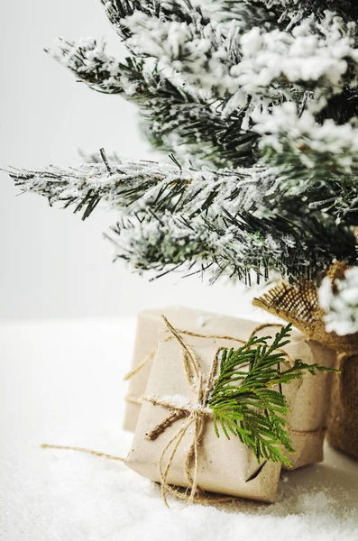 Boîtes sous un arbre artificiel et de la neige. Cadeaux du Père Noël. Style rustique — Photo