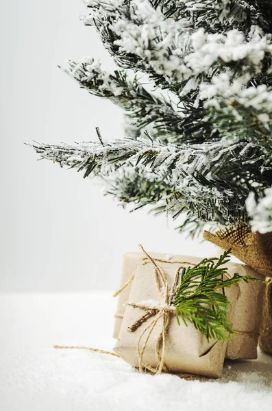 Cajas bajo un árbol artificial y nieve. Regalos de Santa Claus. Estilo rústico — Foto de Stock