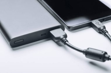 Beyaz arka plan üzerinde güç bankadan şarj siyah telefon smartphone. Modern teknoloji kavramı.