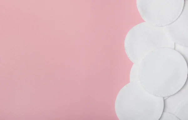 Várias almofadas de algodão para remover a maquiagem em um fundo rosa. Cuidado com o rosto. Vista superior, flat lay, espaço de cópia — Fotografia de Stock