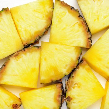 Beyaz ahşap arka planda ananas dilimleri. Tropik sulu, egzotik, sağlıklı meyve dokusu. Üst manzara, düz uzanma