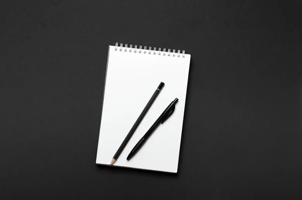 白色开卷笔记本 黑色铅笔和钢笔 黑色背景 写字台文具俯瞰 — 图库照片