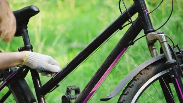 Mężczyzna w rękawiczkach dokręca śruby kluczem do klątwy na ramie roweru górskiego. Pilny remont pojazdu przez mechanika na szosie w letnim lesie. Aktywny tryb życia, sport letni — Wideo stockowe