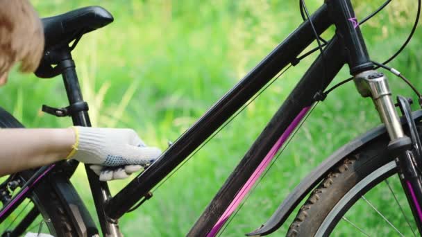 Mężczyzna w rękawiczkach odkręca śruby kluczem do klątwy na ramie roweru górskiego, naprawiając siedzenie rowerowe. Pilny remont pojazdu przez mechanika na szosie w letnim lesie. Aktywny tryb życia, sport. — Wideo stockowe
