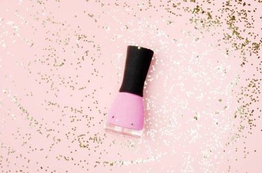 Nail polish bottle on golden glittering background. Pink fingernail varnish on nude backdrop with shiny glitters. Female cosmetics accessory. Elegant manicure enamel, pedicure lacquer top view. clipart