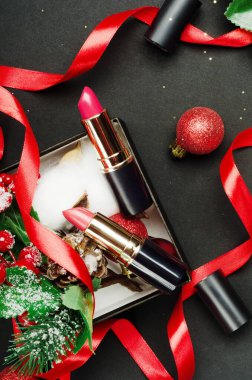Kırmızı ve pembe rujlar üst görüş kompozisyonu. Güzellik endüstrisi ürün konsepti. Siyah üzerine hediye kutusunda makyaj aksesuarı. Kadınlar pofuduk. Yeni yıl, Noel hediyesi fikri. Kozmetoloji özniteliği.