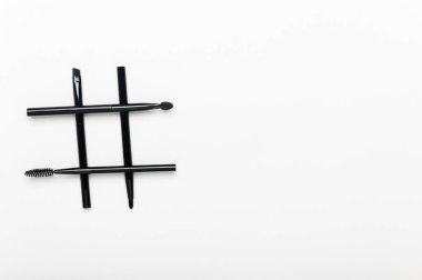 Maskaradan yapılmış etiket ve beyaz arkaplanda göz farı fırçaları. Tasarım için izole edilmiş hash etiketi. Aletleri uydur. Metin için yer alan yaratıcı moda kompozisyonu yatay arkaplan.