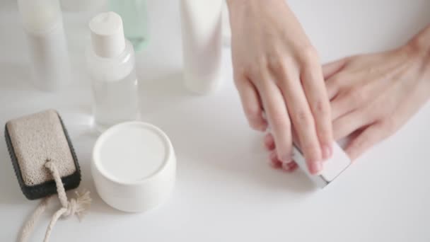 Flickan polerar naglarna med en nagelfil hemma. Skönhet manikyr förfarande hemma under karantän och isolering. Tillbehör för nagellackering. Kosmetiska handvårdsprodukter — Stockvideo