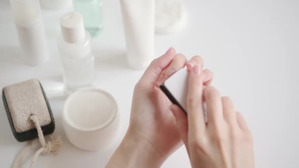 Das Mädchen poliert ihre Nägel zu Hause mit einer Nagelfeile. Schönheitskur zu Hause während Quarantäne und Isolation. Zubehör zum Nagellack. Kosmetische Handpflegeprodukte — Stockvideo