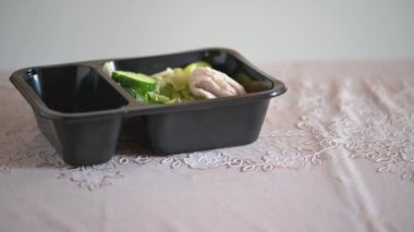Bir kadın masaya sağlıklı bir salatayla plastik bir kap koyar ve yer. Çatalla yakın plan kadın eli. Ev yapımı yemekler bir restorandan geliyor, telefonla sipariş ediliyor. Diyet, sağlıklı atıştırmalık