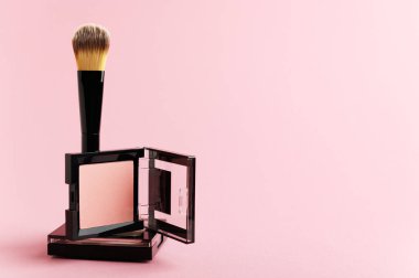 Beyaz arka planda makyaj malzemeleri olan kompozisyon. Siyah fırça, makyaj malzemesi, rengarenk zeminde allık ve toz paketi. Yüzü, dudakları ve gözleri için kopya alanı olan güzellik ürünleri..