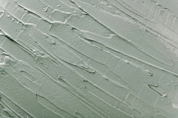 Yüz maskesi ve kozmetik ovalama dokusu yakından. Kadın hijyeni ve cilt bakımı. Akrilik boya fırça darbeleri arka planda. Güzellik ürünü, spa salonu prosedürü. Gri arkaplan için çamur maskesi.