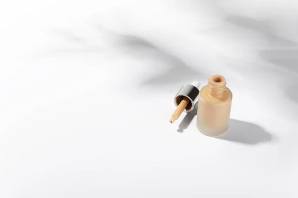 Sıvı fondöten, pipetli krema şişesi. Markasız cam kaplama, hafif arka planda kozmetik ürünler. Güzellik ve kozmetoloji markalaşma konsepti. Boşluğu sol tarafa kopyala.