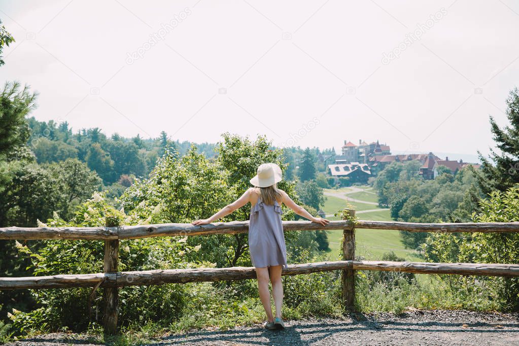 beautiful young woman looking at picturesque summer rural landscape