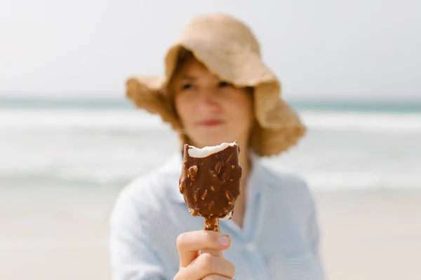 太陽が降り注ぐビーチでアイス クリームを食べて美しい若い女性 — ストック写真