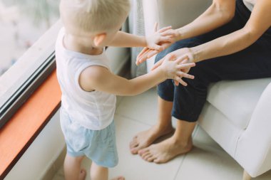 Mutlu sevgi dolu aile. Anne ile oğlu pencerenin yakınındaki yatak odasında oynarken