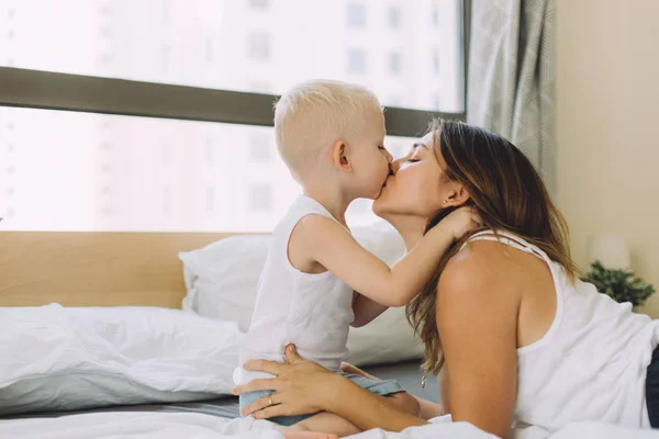 Mother kissing her little son at home