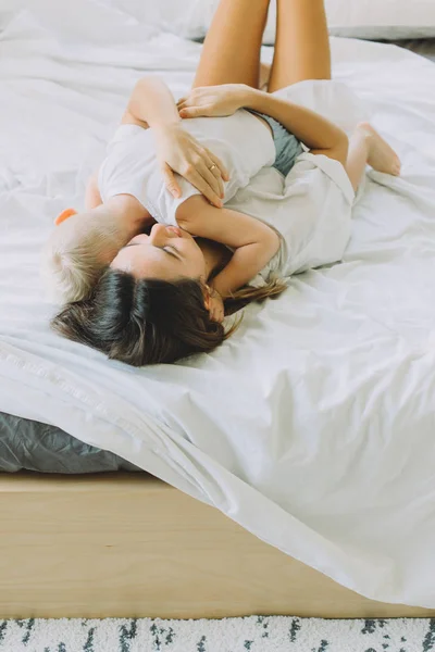 幸せな愛情のある家族 母はベッドの上に横たわる寝室で彼女の息子を抱いて — ストック写真