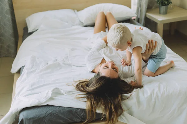 幸せな愛情のある家族 母の寝室のベッドに横になっている息子と遊ぶ — ストック写真