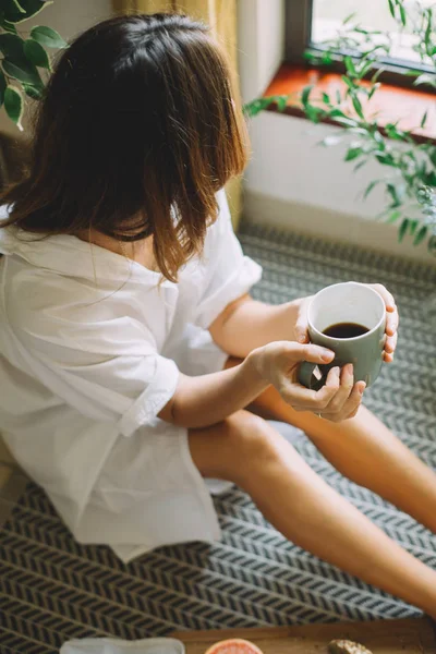 Wanita Muda Memegang Secangkir Kopi Dan Duduk Dekat Jendela — Stok Foto