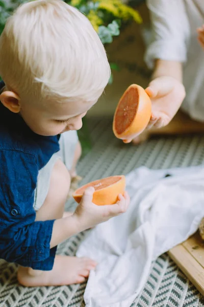 Маленький Мальчик Держит Половину Грейпфрута Смотрит — стоковое фото