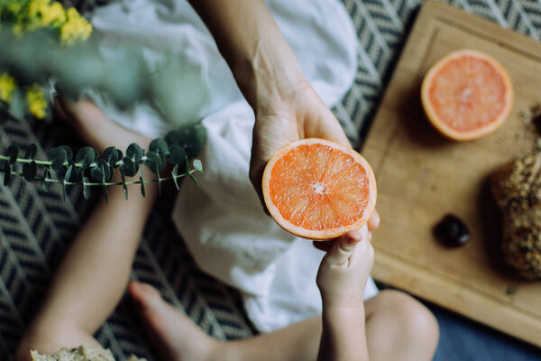 Mother passing a half of grapefruit to her son. Close up shot