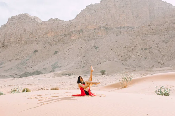 日の出山と砂漠でヨガの赤いドレスの若い美しい女性 — ストック写真