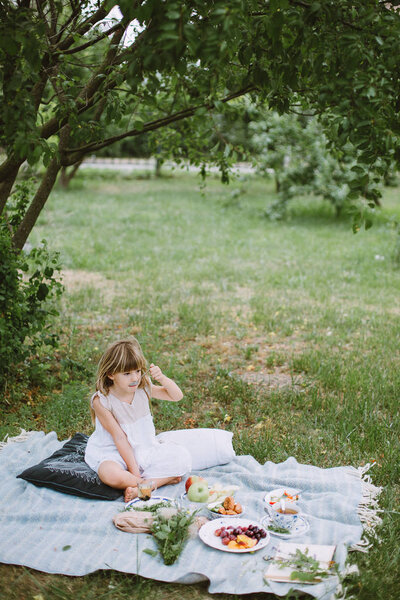 Little girl in the garden with a picnic