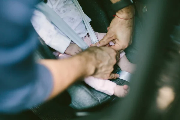 Primer plano de un hombre sujetando un cinturón de seguridad en su bebé recién nacido — Foto de Stock