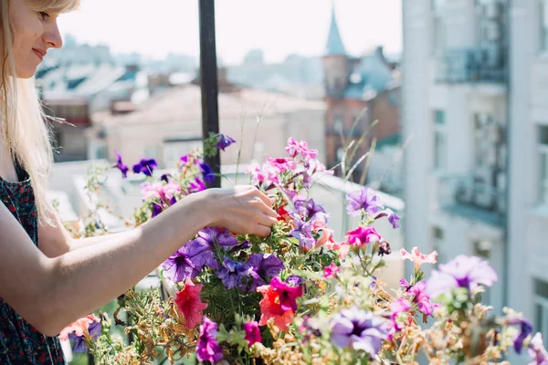 Wanita muda di balkon berkebun. Bunga berwarna-warni dalam pot putih — Stok Foto