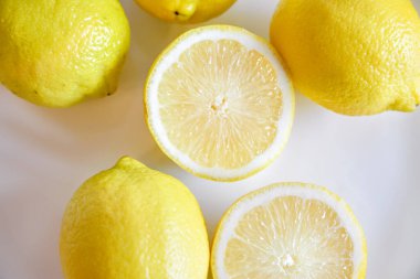 Sulu limonlar ve yarıları beyaz bir tabakta.