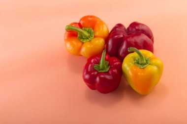 Tatlı bellpepper. İki kırmızı ve hafif pembe bir arka plan üzerinde iki sarı-turuncu tatlı bellpeppers. Dört adet. Stüdyo ışık. Üstten görünüm