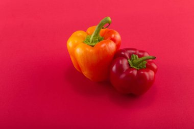Tatlı bellpepper. Kırmızı ve turuncu-sarı kırmızı bir arka plan üzerinde tatlı bellpeppers. İki parça. Stüdyo ışık. Üstten görünüm