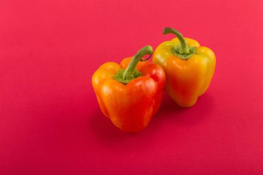 Tatlı bellpepper. Kırmızı bir arka plan üzerinde iki turuncu-sarı tatlı bellpeppers. İki parça. Stüdyo ışık. Üstten görünüm