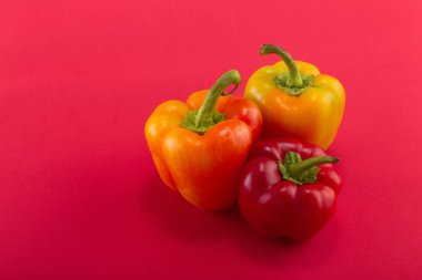 Tatlı bellpepper. İki portakal-sarı ve kırmızı bir arka plan üzerinde kırmızı bir tatlı bellpeppers. Üç parça. Stüdyo ışık. Üstten görünüm
