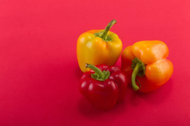 Tatlı bellpepper. İki portakal-sarı ve kırmızı bir arka plan üzerinde kırmızı bir tatlı bellpeppers. Üç parça. Stüdyo ışık. Üstten görünüm