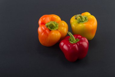 Tatlı bellpepper. İki portakal-sarı ve siyah bir arka plan üzerinde kırmızı bir tatlı bellpeppers. Üç parça. Stüdyo ışık. Üstten görünüm